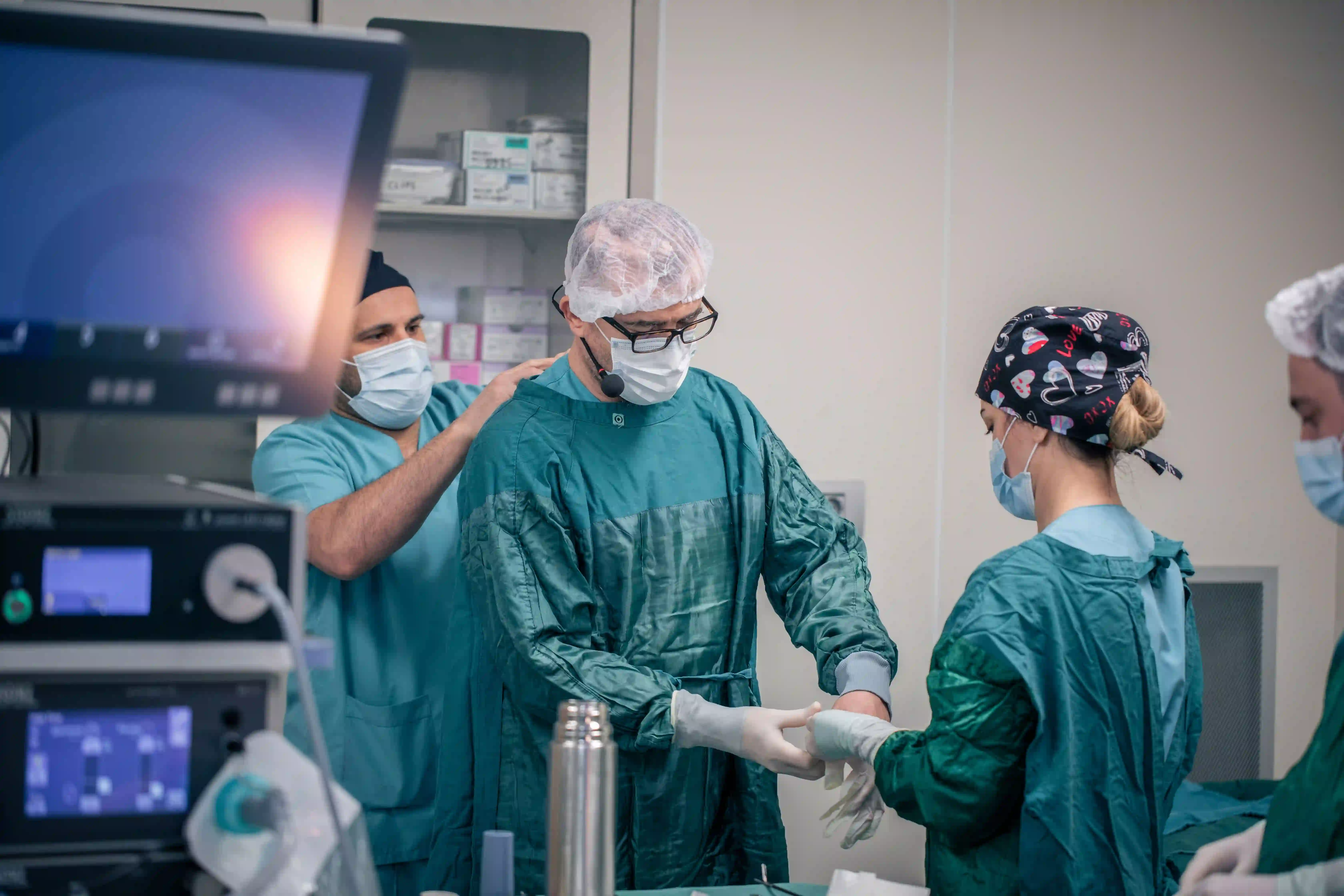 Surgical team in gowns, masks and caps preparing in an operating theatre