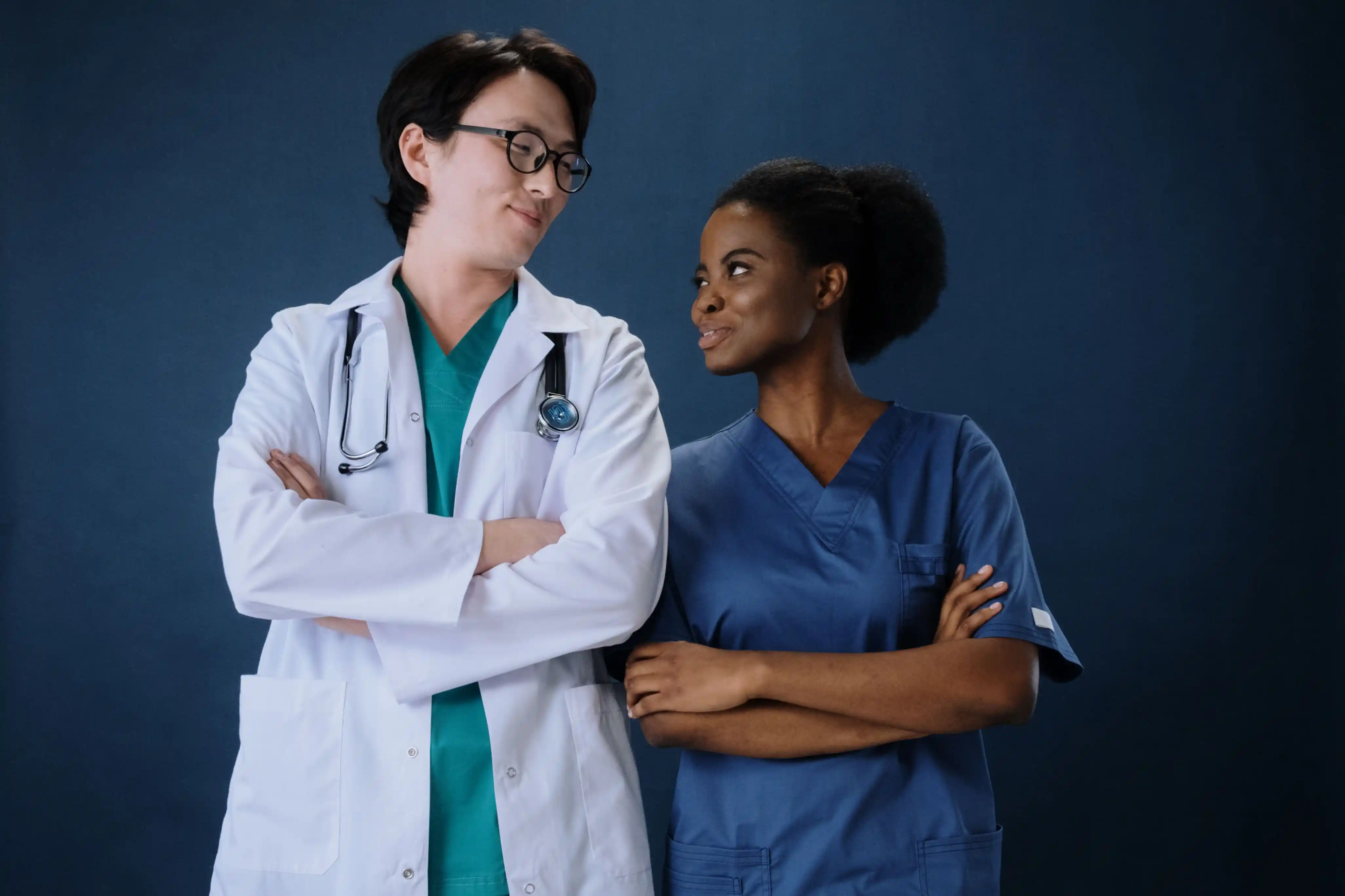 The doctor and the nurse smiling at each other, arms folded